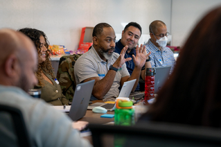 Several people in a meeting with laptops in front of them in conversation 