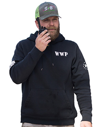 Man in a hoodie talking into a walkie-talkie.