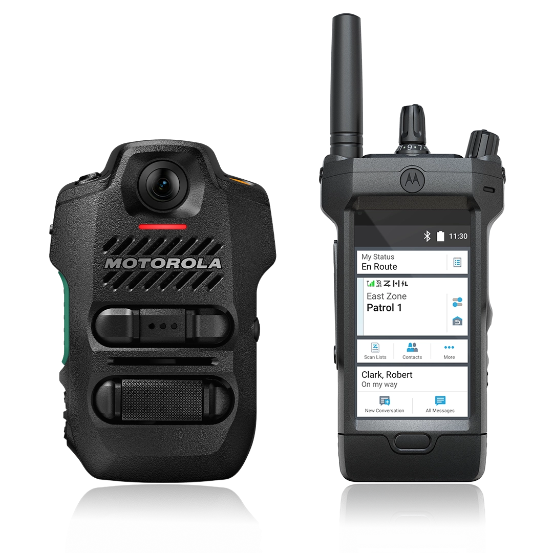 A close-up shot of two Motorola Solutions’ law enforcement devices side-by-side. On the left is a black V700 body camera and speaker microphone unit. On the right is a handheld smart radio with an antenna and control knobs at the top. Its touchscreen display shows a dispatch interface with the status, location, and a message notification.