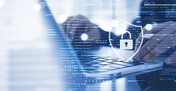 Person types on a laptop with graphics representing cybersecurity