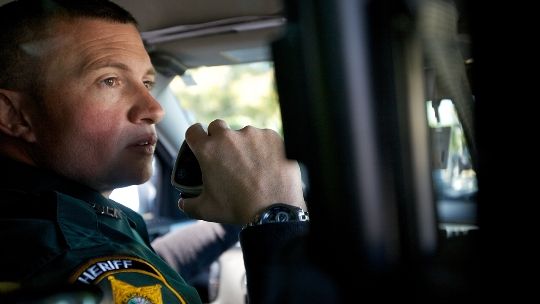 Image of a police officer talking on a remote speaker microphone
