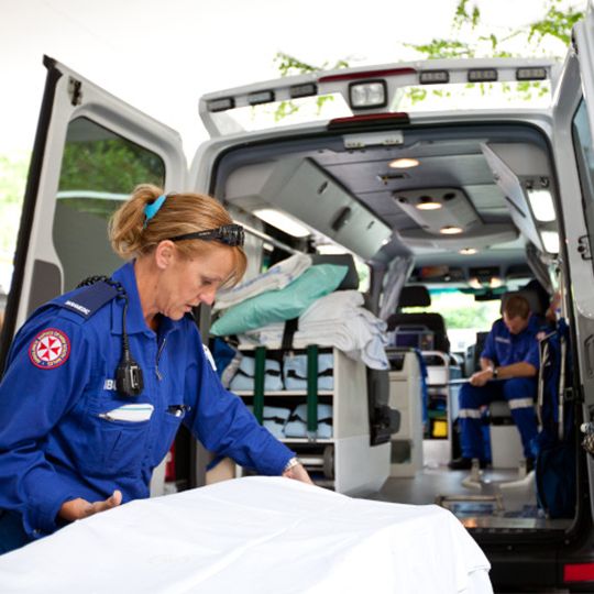 Paramedic prepares stretcher by ambulance.