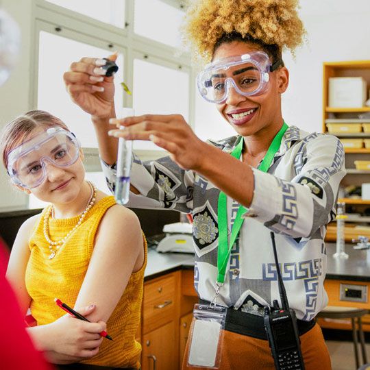 Science teacher and student in the classroom doing an experiment. 