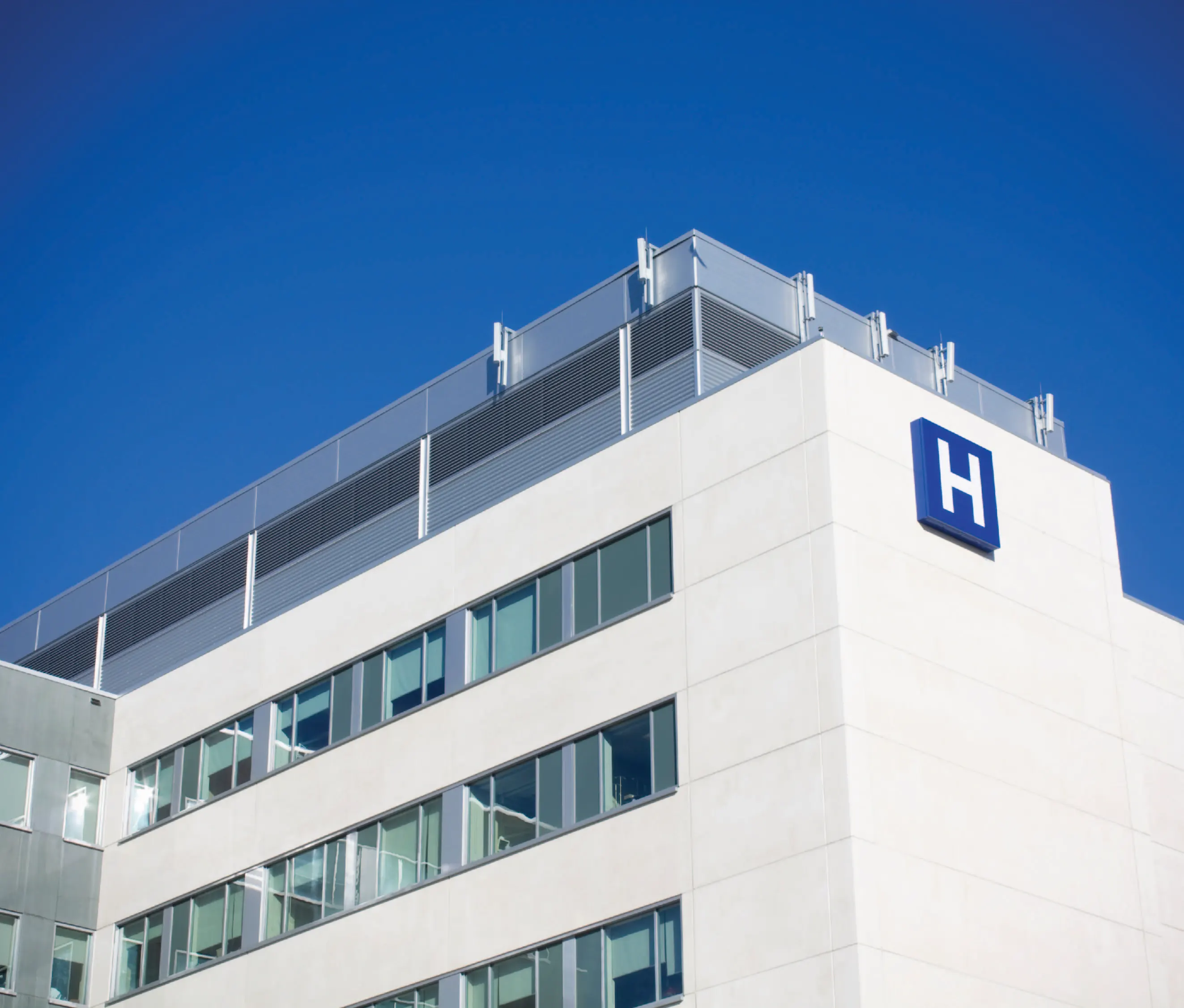 Outside view of a hospital, marked with a blue H sign
