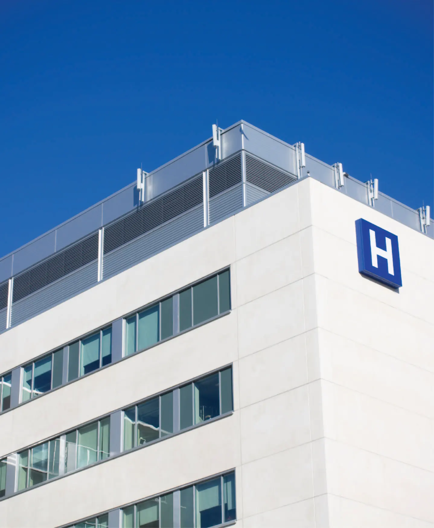 Outside view of a hospital, marked with a blue H sign