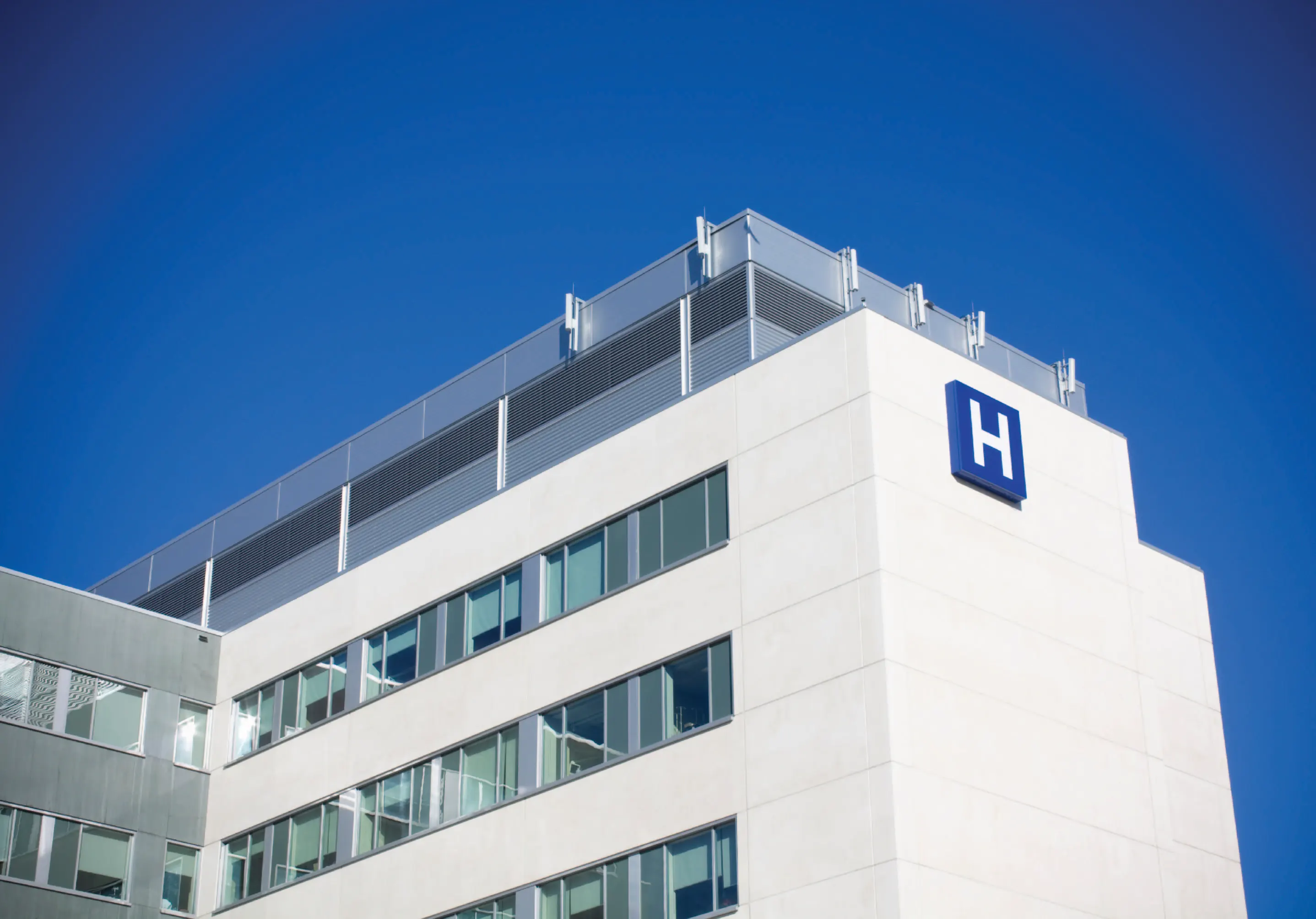 Outside view of a hospital, marked with a blue H sign