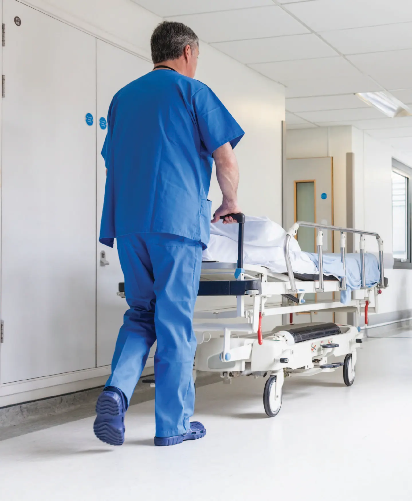 Hospital worker pushing patient in medical trolley