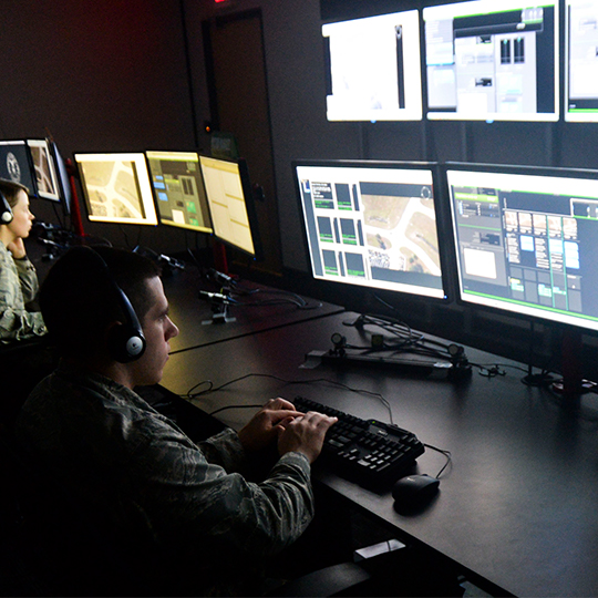 Man in military uniform monitoring computer screens