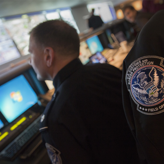 Man monitoring computer screens with colleague. 