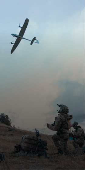 Image of members of the military in camouflage outfit operating a drone in an open field