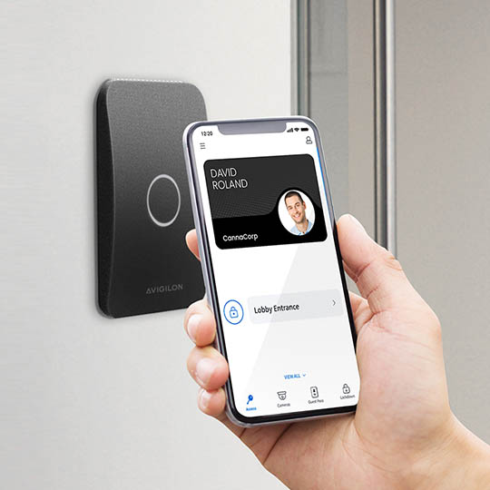 hand holding up a smartphone to an access control smart reader
